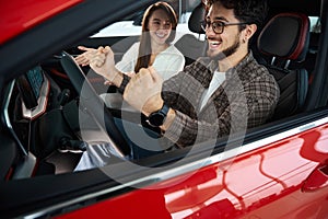 Overjoyed man and woman sitting in new auto celebrating buying new car