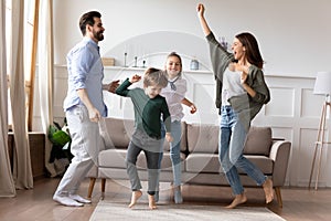 Overjoyed married couple dancing to favorite music with kids.