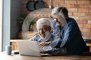 Overjoyed mature couple using laptop together, reading good news