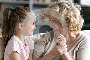 Overjoyed mature grandmother have fun talking with little granddaughter photo