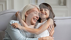 Overjoyed mature grandmother playing with little granddaughter at home