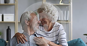 Overjoyed middle aged family couple relaxing on comfortable sofa.