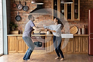 Overjoyed millennial couple dancing at kitchen excited with relocation