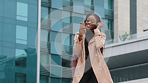 Overjoyed millennial girl wearing headphones have fun moving listening music outdoor, happy young woman in earphones