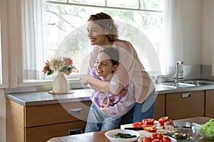 Overjoyed mother and teen daughter have fun cooking together