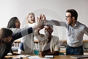 Overjoyed multiracial colleagues give high five engaged in teambuilding