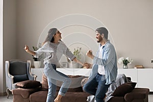 Overjoyed multiracial couple dance together at home