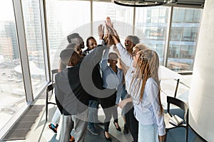 Overjoyed multiracial employees give high five at meeting