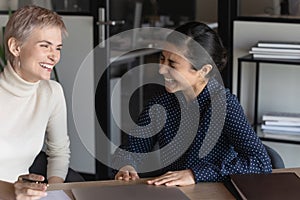 Overjoyed multiracial female colleagues laugh at workplace