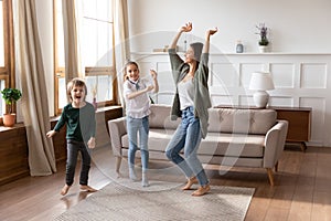 Overjoyed mum have fun dance with little kids at home