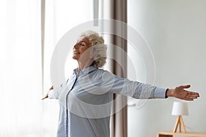 Overjoyed old woman stretch at home feeling positive