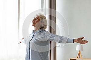 Overjoyed old woman stretch at home feeling positive photo