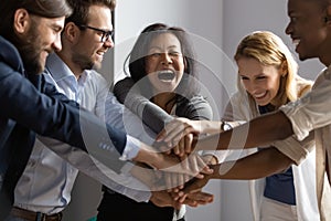 Overjoyed older asian businesswoman joining hands with young multiracial coworkers.