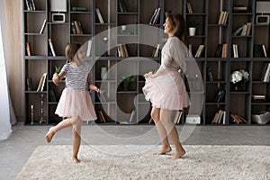 Overjoyed older and younger sisters dressed in pettiskirts dance together