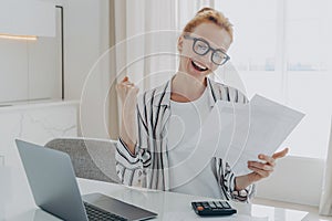 Overjoyed redhead woman exclaiming yes, celebrating money refund or last last mortgage payment