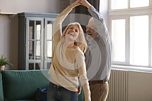 Overjoyed senior couple relax dancing at home