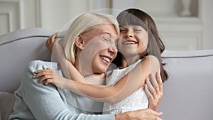 Overjoyed mature grandmother playing with little granddaughter at home photo
