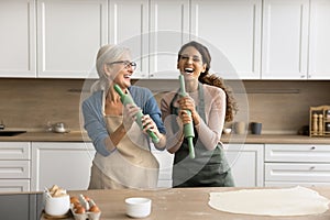 Overjoyed senior mother and adult daughter woman enjoying cooking activity