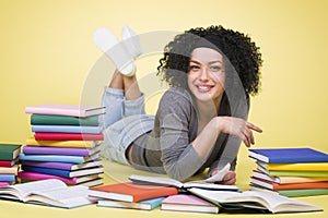 Overjoyed smiling student girl reading surrounded by colorful bo