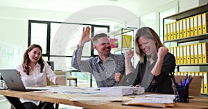 Overjoyed team of employees giving high five and celebrating success in office