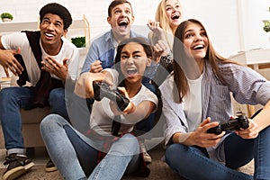 Overjoyed teen friends playing video games at home