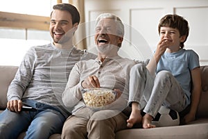 Overjoyed three generations of men watch TV