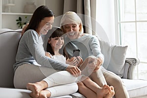 Happy three generations of women relax using cellphone photo