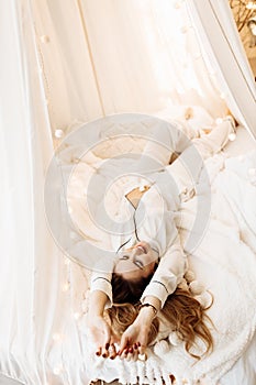 Overjoyed woman laying in canopy bed, chilling, smiling, gorgeous lady resting, enjoy vacations, spend winter holidays