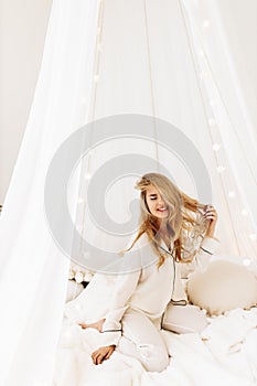 Overjoyed woman laying in canopy bed, chilling, smiling, gorgeous lady resting, enjoy vacations, spend winter holidays