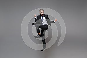 Overjoyed young business man in classic black suit shirt tie posing isolated on grey background. Achievement career