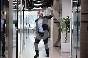 Overjoyed young businessman in suit celebrating job promotion.