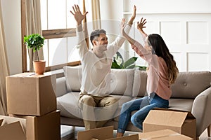 Overjoyed young family couple celebrating relocation in new house apartment.