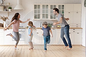 Overjoyed young family dancing with little kids at home