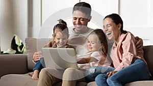 Overjoyed young family laugh using laptop together