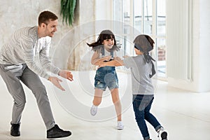 Overjoyed young father playing with laughing daughter and son.