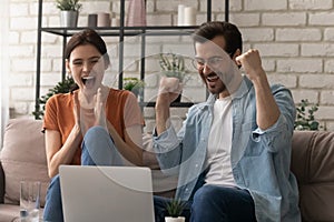 Overjoyed young husband wife scream yes as winners by laptop