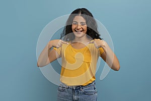 Overjoyed young indian woman pointing at herself and laughing