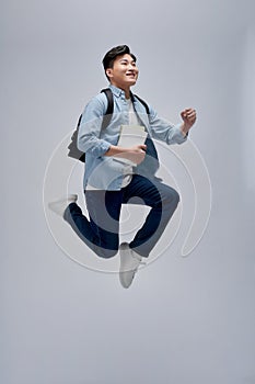 Overjoyed young student man jumping and gesturing happiness isolated on white background