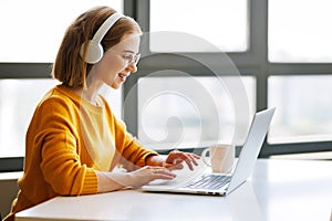 Happy young female having video call while working remotely or studying online on laptop from home photo