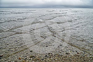 Overlapping, intersecting waves on seashore with dramatic cloudy sky. Natural background, pattern, texture of water. Interference