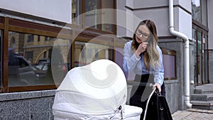 Overloaded business mother talking phone and swinging infant carriage, balance