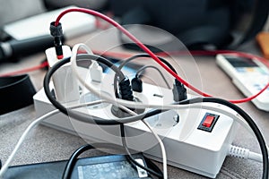 Overloaded power socket plug extendion at home. Tangled cords of home appliances and chargins gadgets mess