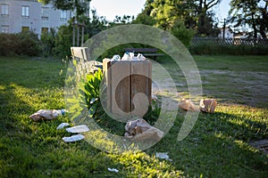 Overloaded trash bin with plastic on grass, garbage dump in public zone, environmental problem