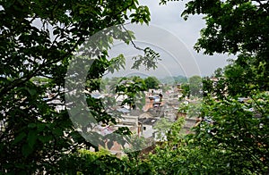 Overlook to ancient town from woody hillside in cloudy spring