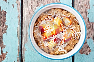 Overnight breakfast oats with peach and coconut on blue wood