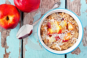 Overnight breakfast oats with peach and coconut on rustic wood photo