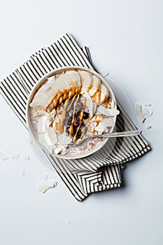 Overnight oatmeal with banana, berries, coconut chips and peanut butter