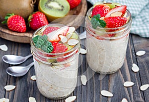 Overnight oatmeal with fresh strawberry and kiwi, garnished with sliced almond in glass jar