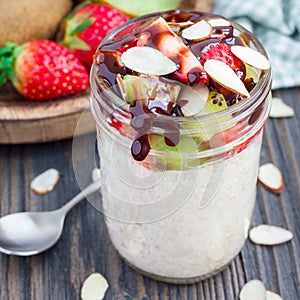 Overnight oatmeal with fresh strawberry and kiwi in glass jar, square format