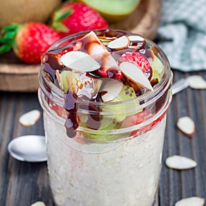 Overnight oatmeal with fresh strawberry and kiwi in glass jar, square
